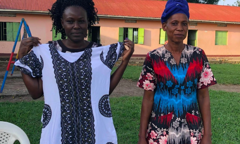 Nabukenya Rashida (tv) viser en af sine nyeste kreationer frem. Til højre ses skolelærer på Kakundi Community School Akello Hellen Rose i en af sine yndlingskjoler, som er syet af Rashida. Foto: Sara Vorre Rothstein.